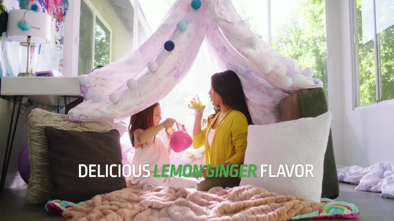 A mother and daughter under a blanket fort — “Delicious Lemon Ginger flavor.”